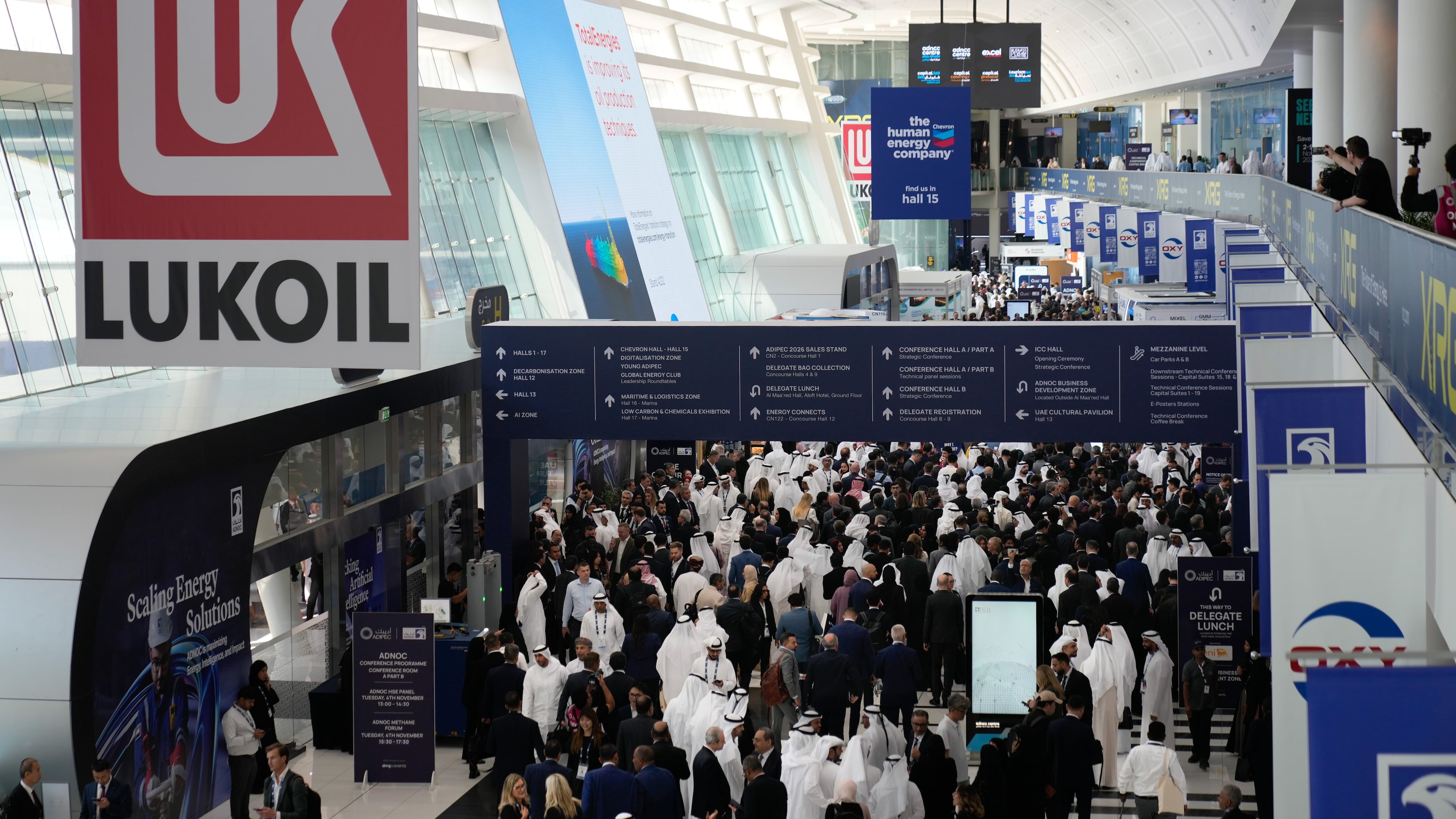 Logo of Russian oil company Lukoil hangs from the ceiling as visitors and delegates leave the hall after the inaugural session of annual Abu Dhabi International Petroleum Exhibition & Conference (ADIPEC) in Abu Dhabi, United Arab Emirates, Monday, Nov. 3, 2025. (AP Photo/Altaf Qadri)