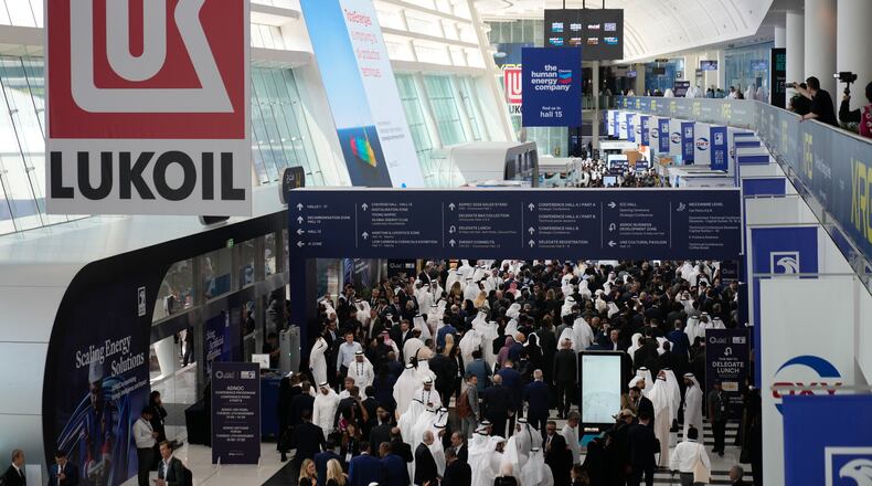 Logo of Russian oil company Lukoil hangs from the ceiling as visitors and delegates leave the hall after the inaugural session of annual Abu Dhabi International Petroleum Exhibition & Conference (ADIPEC) in Abu Dhabi, United Arab Emirates, Monday, Nov. 3, 2025. (AP Photo/Altaf Qadri)