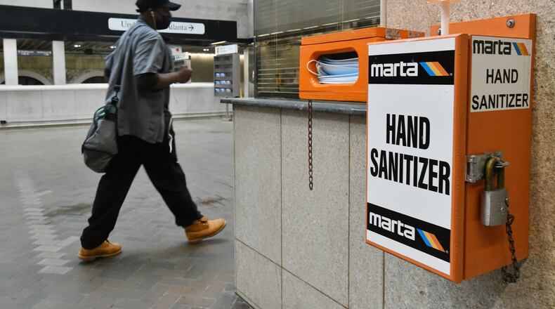 A Marta customer walks past mask and hand sanitizer dispensers at the Five Points MARTA station on Thursday, March 25, 2021. (Hyosub Shin / Hyosub.Shin@ajc.com)