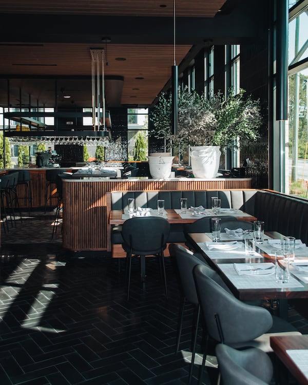 A restaurant bar and dining room with large windows with sunlight pouring in