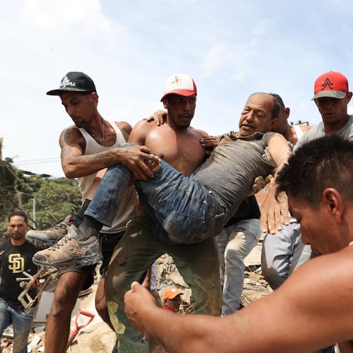 Neighbors carry a man rescued from the rubble of a collapsed building the day after earthquakes struck La Guaira, Venezuela, Thursday, June 25, 2026. (AP Photo/Pedro Mattey)