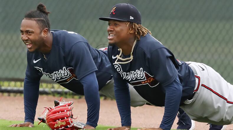 Ozzie Albies (left) and Ronald Acuna hit the ground for pushups in the outfield after missing fly balls during batting practice Feb. 21, 2020, at spring training workouts in North Port, Fla.