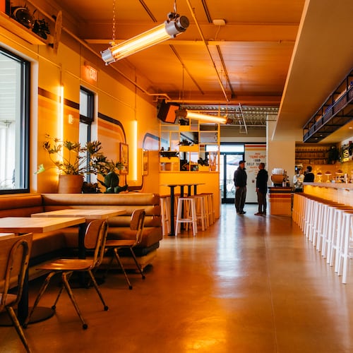 A long shot of the dining room at Muchacho with tables on the left and a bar/counter on the right.