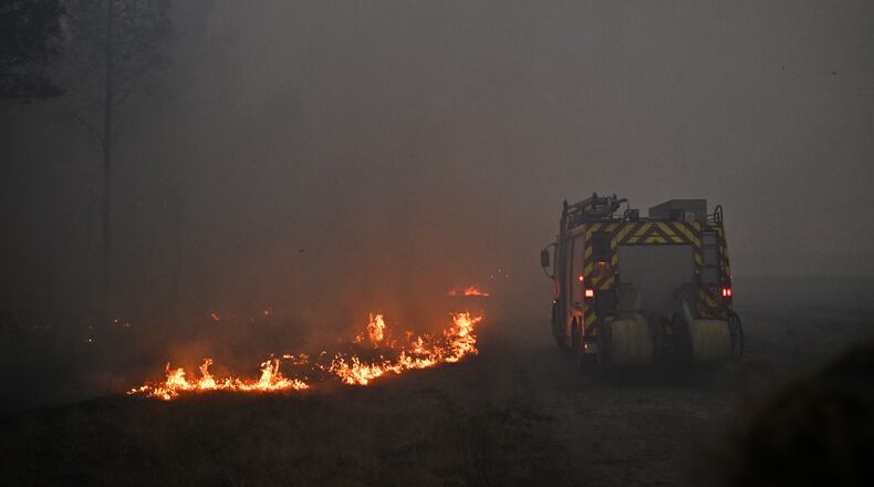 A fire engine drives through smoke of a wildfire raging near Marcheprime, outside, Bordeaux, France, Sunday, July 26, 2026. (AP Photo/Emma Da Silva)