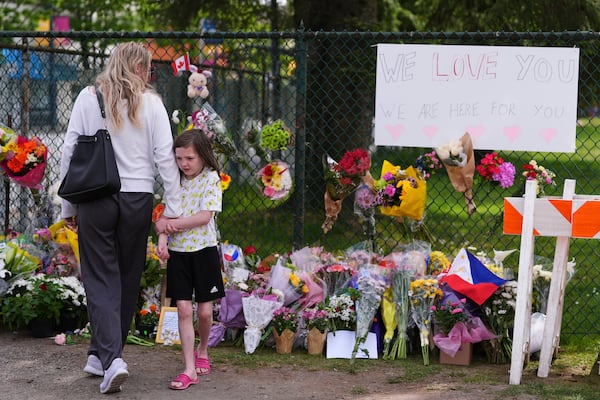 Visitors stand near a growing memorial the day after a driver killed multiple people during a Filipino community festival Sunday, April 27, 2025, in Vancouver, British Columbia. (AP Photo/Lindsey Wasson)