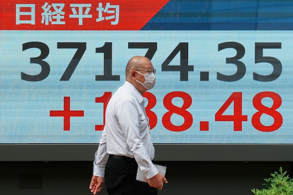A person walks in front of an electronic stock board showing Japan's Nikkei index at a securities firm Friday, May 23, 2025, in Tokyo. (AP Photo/Eugene Hoshiko)