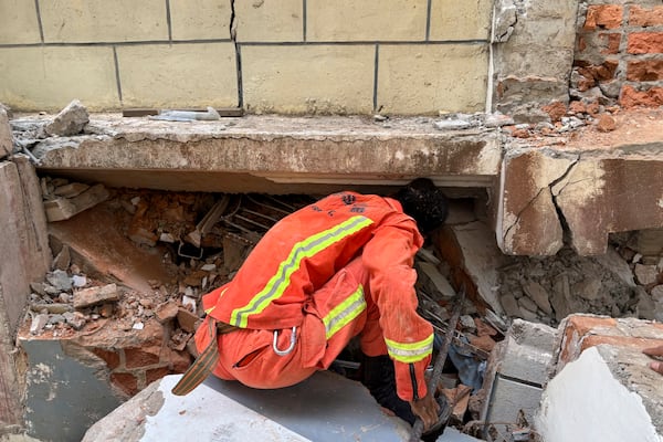 A firefighter recovers the belongings of victims from damaged buildings that house Governments' servants in Naypyitaw, Myanmar, Monday, April 28, 2025, one month after the earthquake. (AP Photo/Aung Shine Oo)