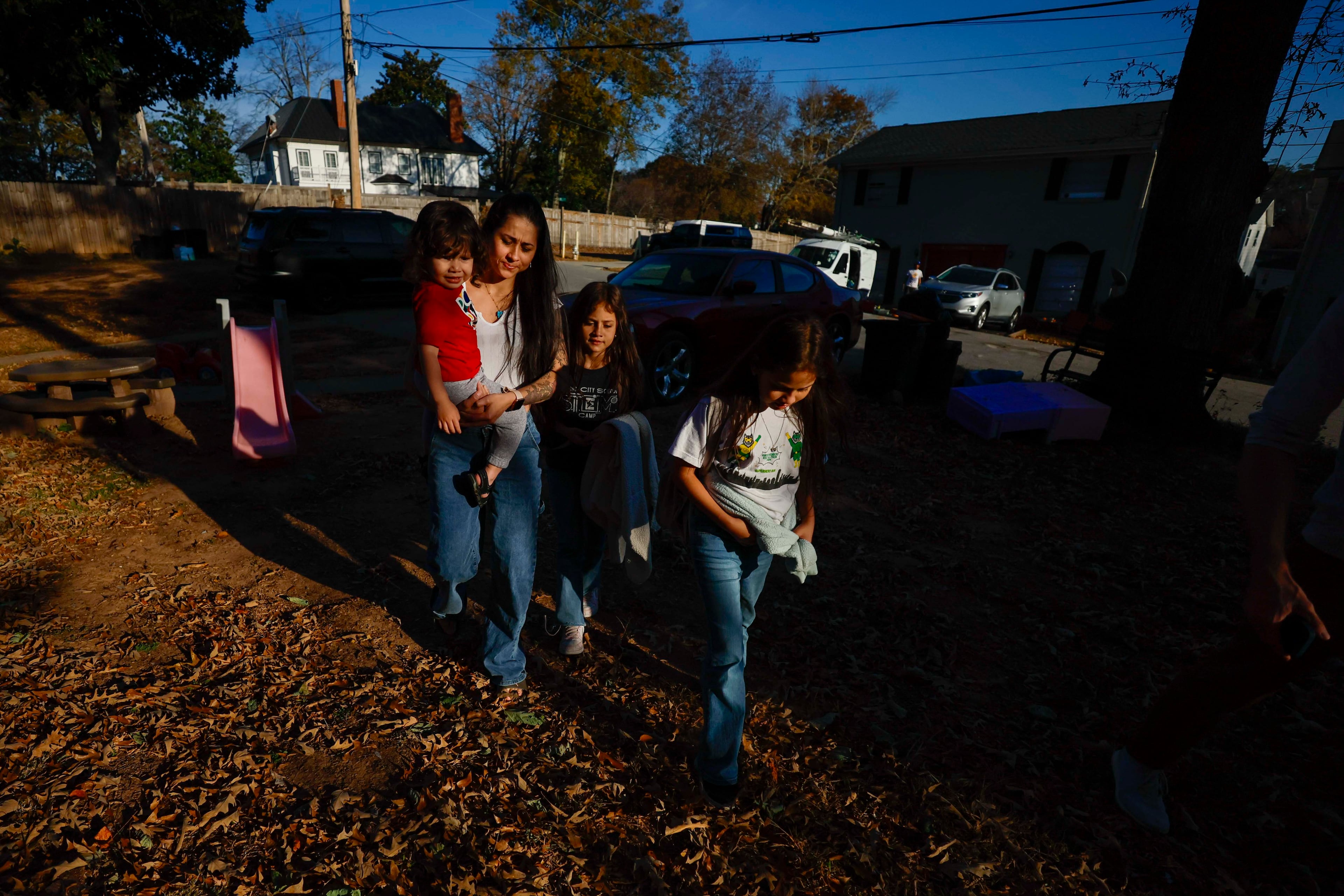 Ceudy Gutierrez walks with her kids, Maria Jose, Maria Camila, and Matias (2), after getting the twin sisters off the school bus on Tuesday, Nov. 18, 2025. (Miguel Martinez/ AJC)
