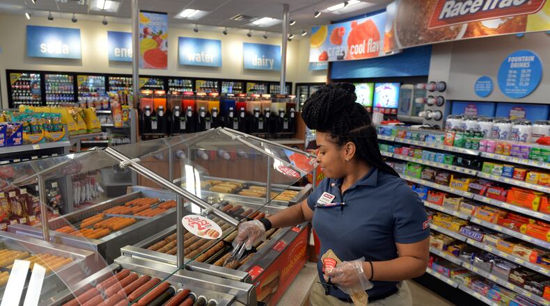 Racetrac employee Jeanique Chestnut stocks the hot food bar at a Smyrna store in February. The metro Atlanta-based company has updated its benefits package with more paid leave for parents.BRANT SANDERLIN / BSANDERLIN@AJC.COM