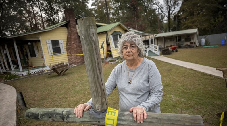 RINCON, GA - NOVEMBER 14, 2023: Beverly Smithey stands next to a cross her husband Gregory built in their front yard, Tuesday, Nov. 14, 2023, in Rincon, Georgia. Gregory died while trapped in a bathroom at the rear of the home after a propane gas explosion destroyed their home. (AJC Photo/Stephen B. Morton)