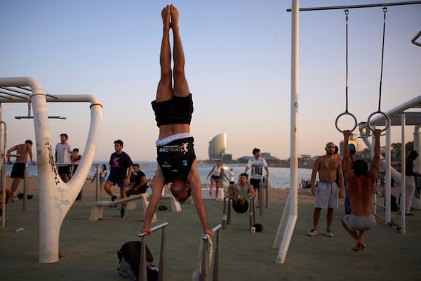 People work out in an open-air gym next to the beach in Barcelona, Spain, Tuesday, June 25, 2025. (AP Photo/Emilio Morenatti)