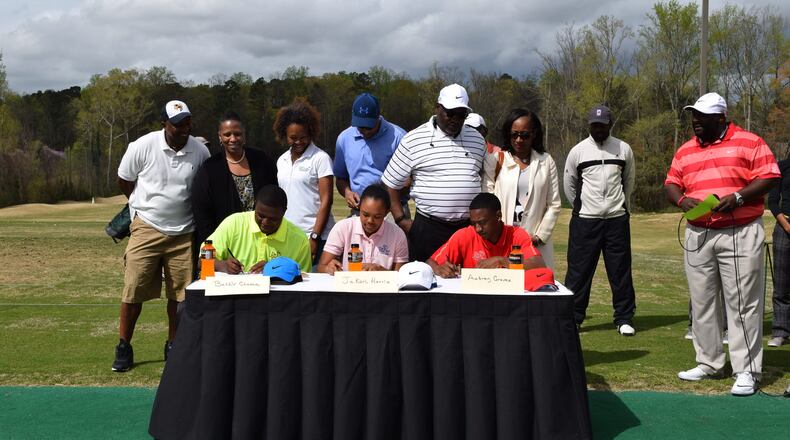 (L-R) Bashir Chuma, Jakari Harris and Aubrey Graves sign their scholarship papers.