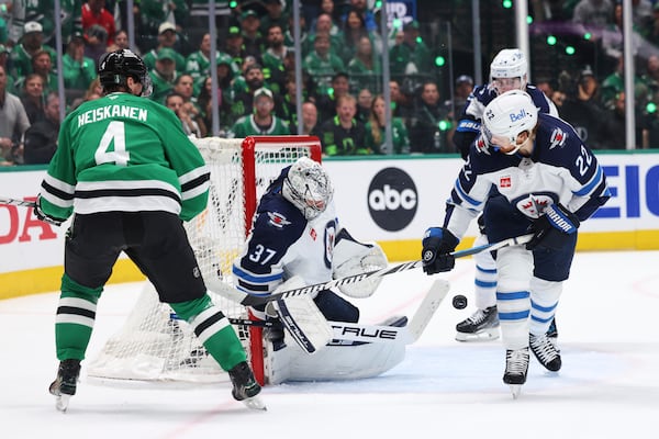 Winnipeg Jets goaltender Connor Hellebuyck (37) blocks a shot as center Mason Appleton (22) helps against pressure from Dallas Stars defenseman Miro Heiskanen (4) in the first period of Game 6 of a second-round NHL hockey playoff series in Dallas, Saturday, May 17, 2025. (AP Photo/Gareth Patterson)