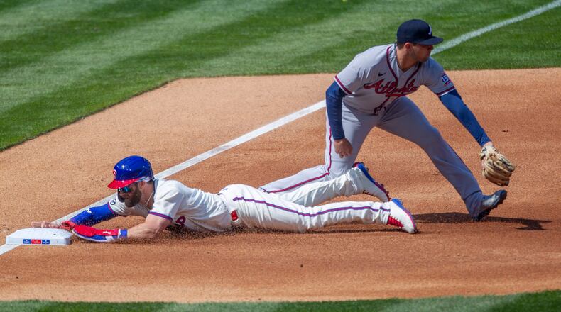 Philadelphia Phillies Bryce Harper slides in safe at third base before Braves third baseman Austin Riley (right) can make the tag during the first inning Sunday, April 4, 2021, in Philadelphia. (Laurence Kesterson/AP)