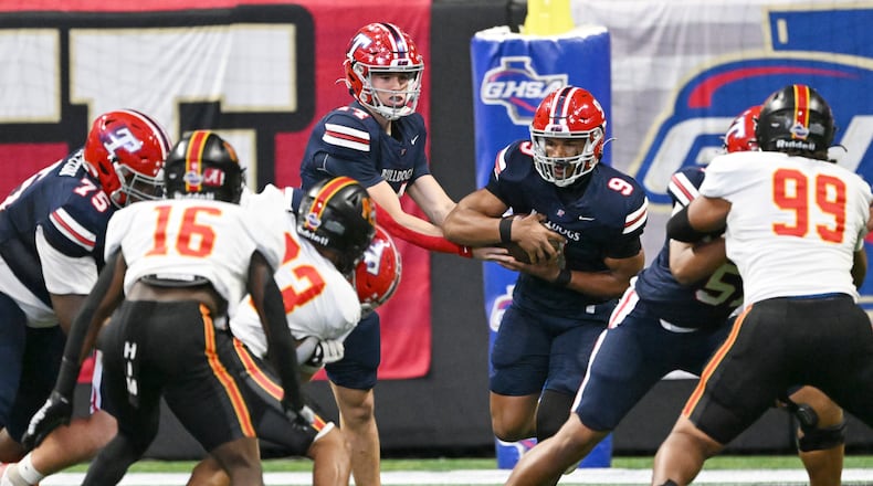 Toombs County's quarterback TJ Stanley (center) makes a handoff to running back Justin Powell during the GHSA Class A Division state championship game at Mercedes-Benz Stadium on Tuesday, Dec. 17, 2024, in Atlanta. Toombs County faces Worth County for the first time next week. (Hyosub Shin/AJC 2024)