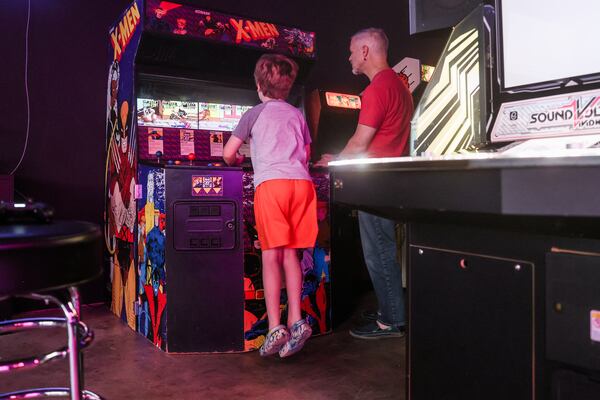 A child jumps with retro-fueled excitement, playing the "X-Men" game at Infinite Horizons Arcade in Tucker. (Abbey Cutrer/AJC)