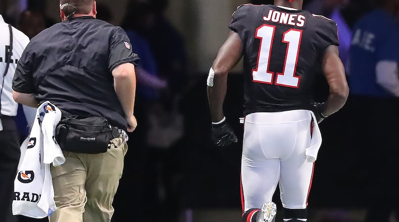 Never a good sign: Falcons wide receiver Julio Jones leaves the field in the first half Sunday for an injury inspection. He didn't return to the game. (Curtis Compton/ccompton@ajc.com)