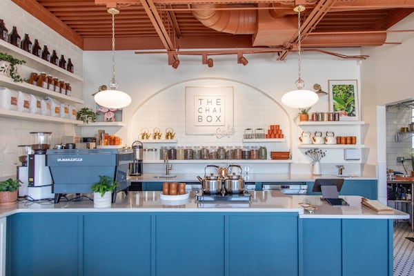 The interior of a light, modern tea shop with an espresso machine and jars of tea