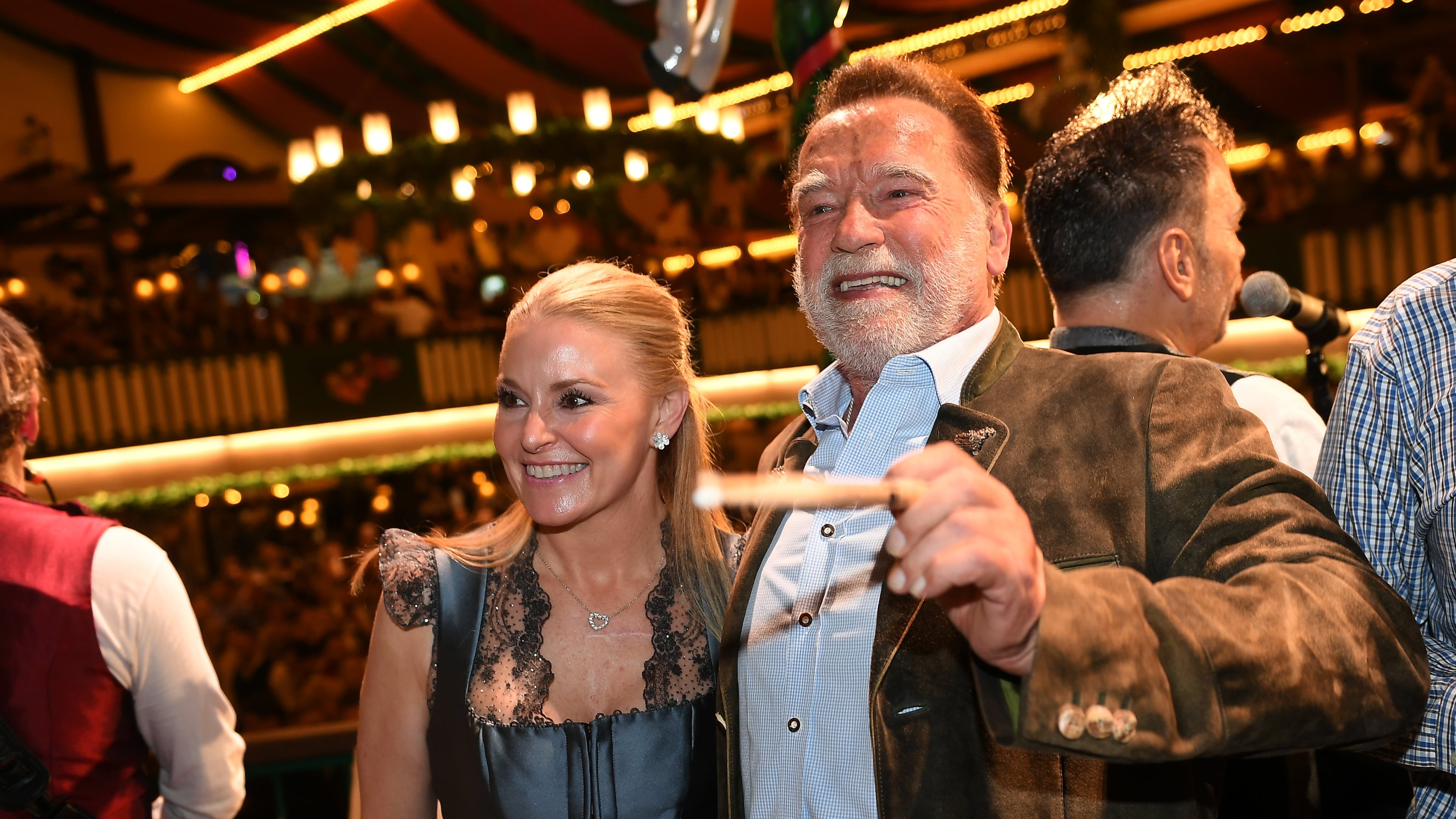 Arnold Schwarzenegger and his partner, Heather Milligan stand on stage during the 190th Oktoberfest on Friday, Sept. 26, 2025, in Munich, Germany. (Felix Hörhager/dpa via AP)