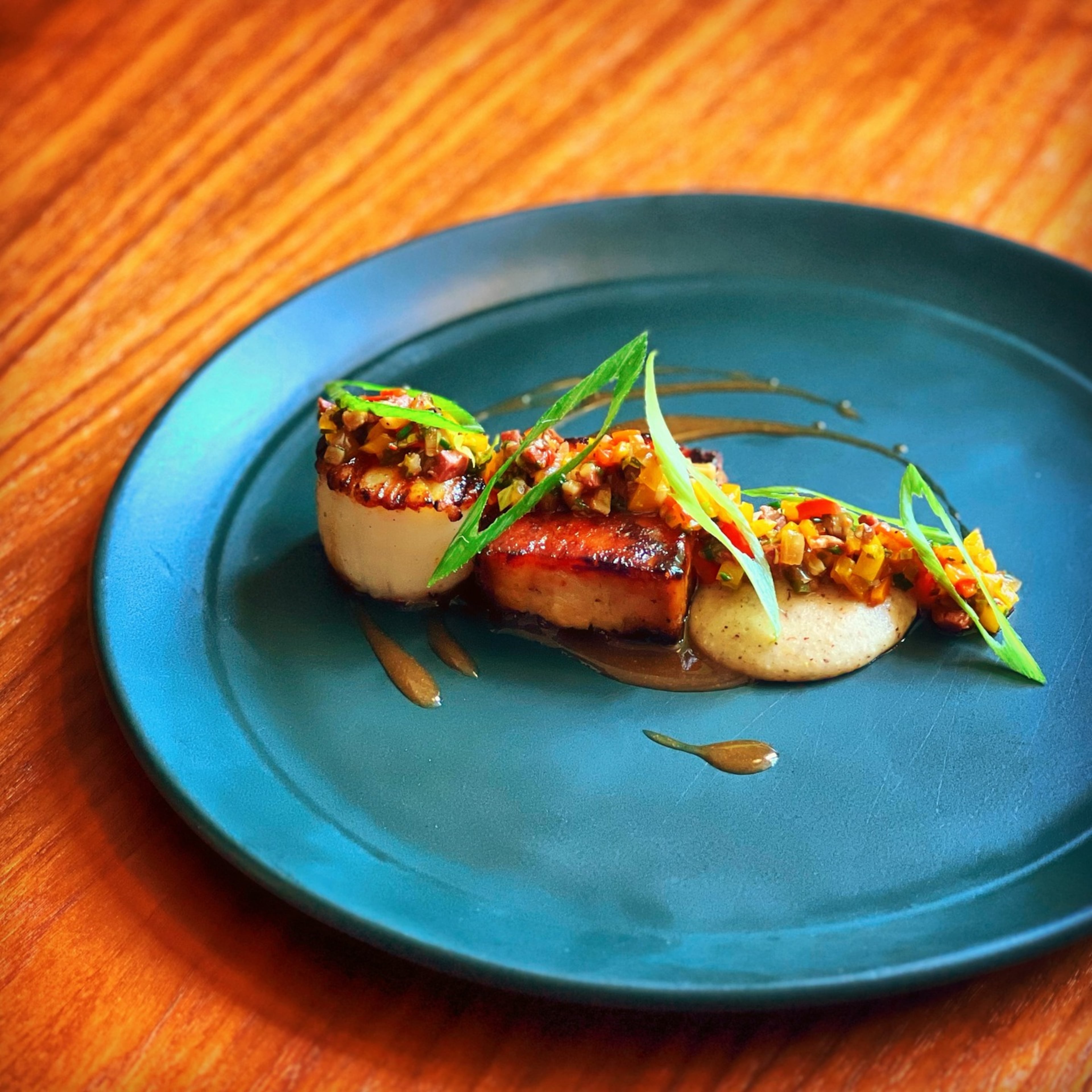 A scallop grilled in minutes is paired with a bit of peach-glazed pork belly that's steamed, smoked and finished on the grill at Nàdair. (Courtesy of Kevin Gillespie)