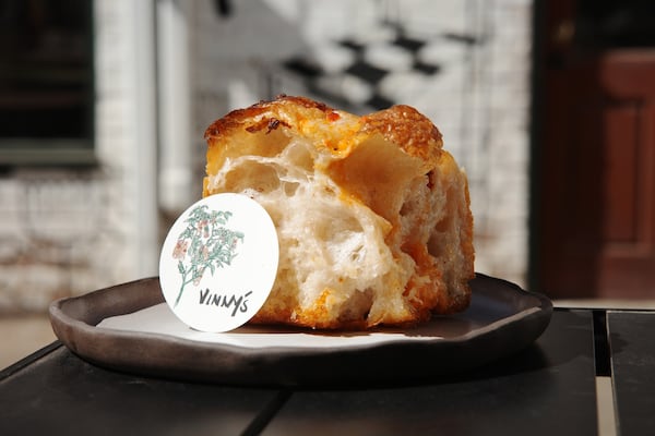 A square piece of airy focaccia sits on a plate with a sticker that says Vinny's next to it.