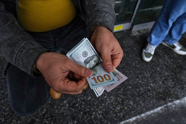 A street money exchanger poses for a photo without showing his face as he counts U.S. dollars at Ferdowsi square, Tehran's go-to venue for foreign currency exchange, in downtown Tehran, Iran, Saturday, April 5, 2025. (AP Photo/Vahid Salemi)