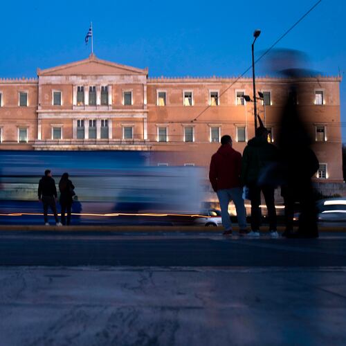 FILE - People stand in front of the Greek Parliament as vehicles drive past in central Athens, on Nov. 21, 2017. (AP Photo/Petros Giannakouris, File)