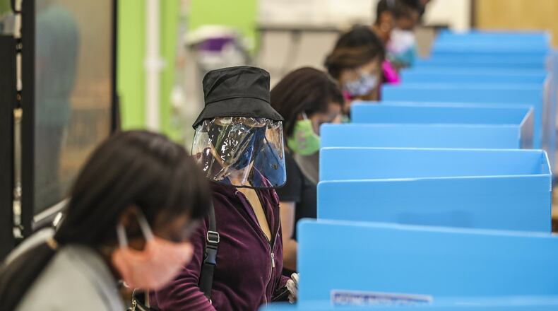 C.K. Hoffler (center) wore a face shield as she voted at Cross Keys High School in DeKalb County on Tuesday. JOHN SPINK/JSPINK@AJC.COM
