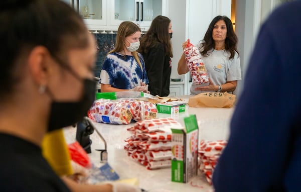Marcy Louza (right) directs a group of volunteers making sandwiches for The Sandwich Project. Two ladies from Dunwoody started making sandwiches for the homeless during the pandemic and this project has expanded into a weekly community service project involving thousands of volunteers all over the metro area. Every week, The Sandwich Project gives away approximately 4,000 to 6,000 sandwiches, plus snacks and fruit to nonprofits for distribution.  PHIL SKINNER FOR THE ATLANTA JOURNAL-CONSTITUTION.