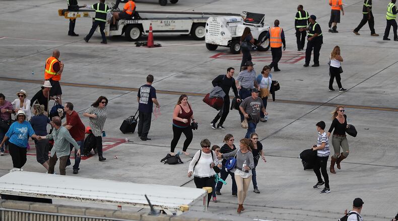People seek cover on the tarmac of Fort Lauderdale-Hollywood International airport after a shooting took place near the baggage claim on January 6, 2017 in Fort Lauderdale, Florida. Officials are reporting that five people were killed and eight wounded in an attack by a single gunman. (Photo by Joe Raedle/Getty Images)