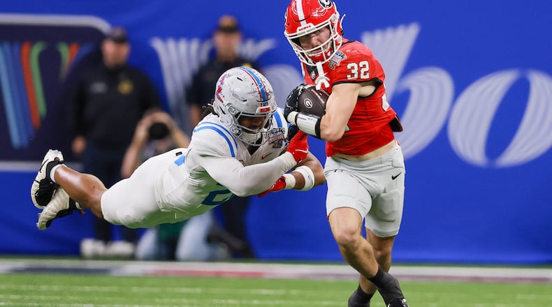 Georgia running back Cash Jones (right) — pictured running for a first down against Ole Miss in the College Football Playoff in January — did a little bit of everything for the Bulldogs after beginning his UGA career as a walk-on. (Jason Getz/AJC)