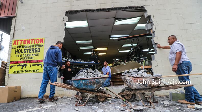Crews with NB Masonry plug the hole left behind by thieves after an early Thursday morning heist at Gable Sporting Goods in Douglasville.