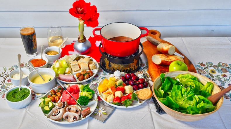 Winter is the perfect time for fondue. In the pot is Chocolate Fondue; the tray below it has accompanying items, such as strawberries, pineapple, pound cake, marshmallows and cherries. The upper tray (left) has items for Cheese Fondue, including sliced apples, crusty bread, gherkins and pickled onions. On the left are sauces for Beef Fondue; the lower tray (left) has items for that fondue, including mushrooms, broccoli, zucchini and roasted potatoes. (Styling by Lisa Hanson / Chris Hunt for the AJC)