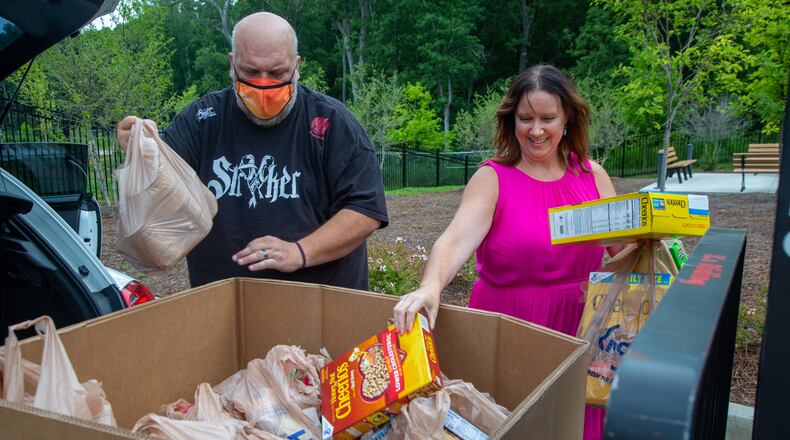 Jason Creed (left) helps Crystal Genter, of the architectural firm Goode Van Slyke, unload donations from her car at the Atlanta Community Food Bank in East Point. The firm is celebrating its 25th anniversary by doing 25 good deeds. PHIL SKINNER FOR THE ATLANTA JOURNAL-CONSTITUTION.
