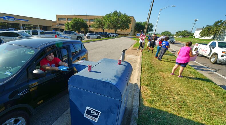 A person drops envelopes into a mailbox as postal workers participate in a national day of action outside a U.S. Post Office building, Tuesday, July 28, 2026, in Fort Worth, Texas. (AP Photo/Julio Cortez)