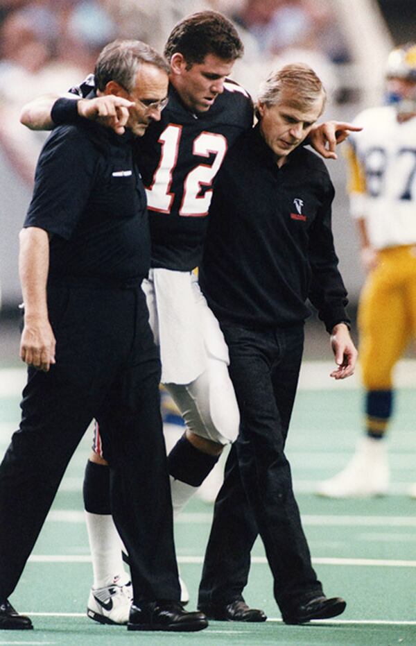 Falcons quarterback Chris Miller is helped off the field after being impaired by a hit. (AJC)