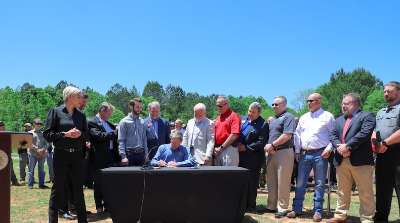 Gov. Brian Kemp, surrounded by state legislators and law enforcement officers at the Barrow County Sheriff's Office gun range, signs a bill into law Friday banning deep cuts into police budgets. Credit: Georgia governor's office