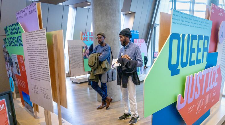 Elliott Abnatha (left) and Jai Kenon look over the traveling exhibit "Queer Justice: 50 Years of Lambda Legal and LGBTQ+ Rights" at the National Center for Civil and Human Rights Saturday, January 6, 2024. (Steve Schaefer/steve.schaefer@ajc.com)