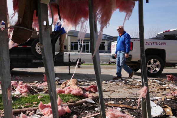 People clean up a damaged warehouse after severe weather passed the area in Carmel, Ind., Thursday, April 3, 2025. (AP Photo/Michael Conroy)