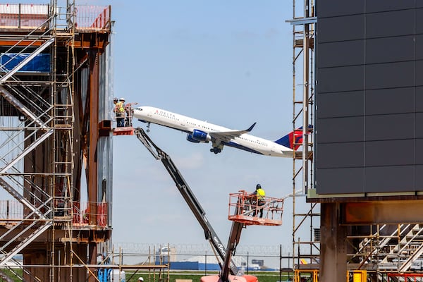 Delta and the airport are in the midst of a major expansion of Concourse D that will last through 2029. Construction workers seen installing panels in the exterior of Modules 3 and 4 as a Delta airplane flies by on Wednesday, March 27, 2024. Once the project is complete, Delta CEO Ed Bastian said, other big ideas for Atlanta's growth will become the focus. (Miguel Martinez/AJC)