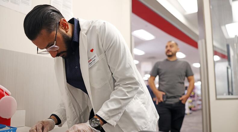 Pharmacist Deep Patel, left, prepares the flu and COVID-19 vaccine for Brandon Guerrero, 34, of Compton, right, at CVS in Huntington Park on Aug. 28, 2024. (Christina House/Los Angeles Times/TNS)
