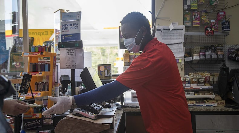 Shell gas-station cashier Bizuayehu Woldegiorgis wears gloves as he rings up a customer inside the convenience store in Snellville on Monday, April 6, 2020. The station’s owner, Suhel Kazani, owns seven Shell gas stations in metro Atlanta. He said that because of the coronavirus pandemic, his gasoline sales are way down. (ALYSSA POINTER / ALYSSA.POINTER@AJC.COM)