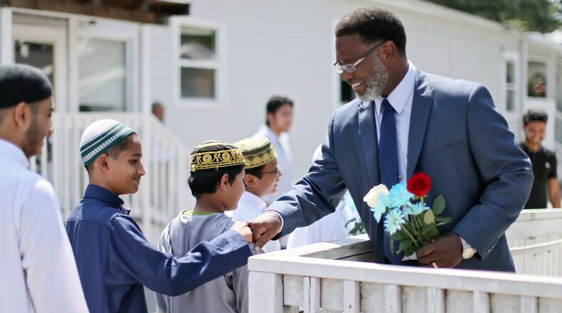 George Lanier (right), pastor of Grace United Methodist Church in Covington, fist-bumps with students at the Masjid At-Taqwa Mosque in Doraville as he is welcomed with flowers on Tuesday, Aug. 23, 2016. BOB ANDRES /BANDRES@AJC.COM