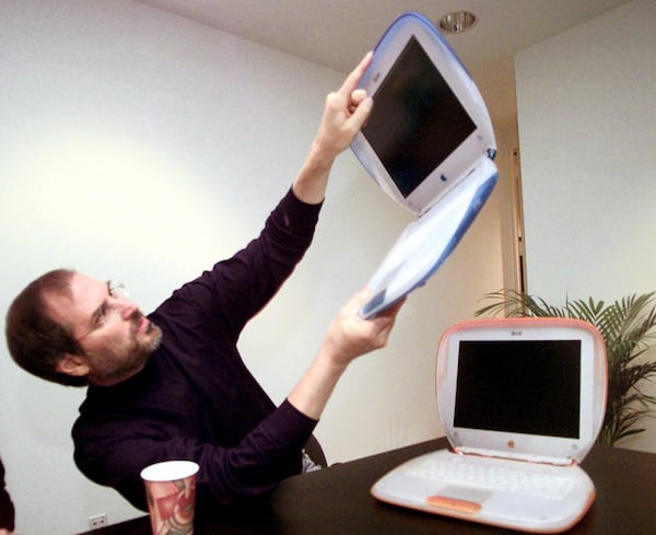 FILE - Steve Jobs, Founder and acting CEO of Apple Computer Inc., holds up one of the company's new consumer laptops called "iBook" after his keynote address at the Macworld Expo in New York, Wednesday July 21, 1999. (AP Photo/Bebeto Matthews, File)