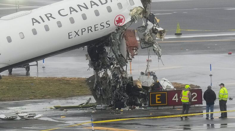FILE - Officials investigate the site, Monday, March 23, 2026, where an Air Canada jet came to rest after colliding with a Port Authority firetruck at LaGuardia Airport, shortly after landing Sunday night in New York. (AP Photo/Seth Wenig, file)