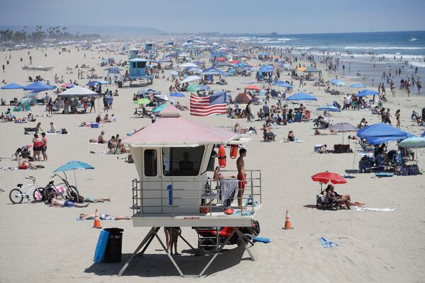 A lifeguard keeps watch over a packed beach Saturday in Huntington Beach, California.