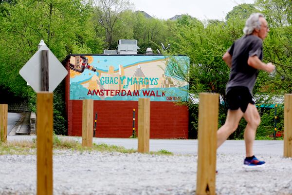A person jogs by the Beltline across from Amsterdam Walk shopping center on Tuesday, April 4, 2023.  Portman Holdings is pursuing a plan to redevelop Amsterdam Walk, a 9-acre shopping center along the Beltline and Piedmont Park.   Miguel Martinez / miguel.martinezjimenez@ajc.com