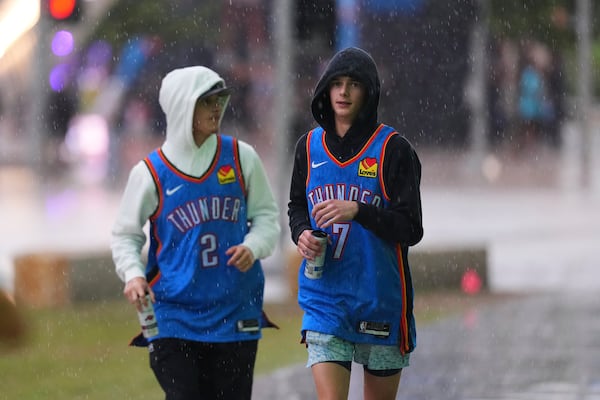 Fans run through the rain before Game 1 of the NBA Finals basketball series between the Indiana Pacers and the Oklahoma City Thunder Thursday, June 5, 2025, in Oklahoma City. (AP Photo/Nate Billings)