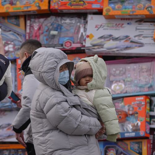 People carry their toddlers by a toy store in Beijing, Monday, Jan. 19, 2026. (AP Photo/Andy Wong)