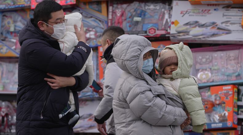 People carry their toddlers by a toy store in Beijing, Monday, Jan. 19, 2026. (AP Photo/Andy Wong)